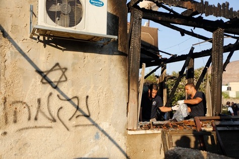 la police israélienne inspecte la maison incendiée de la famille Dawabcheh dans le village de Douma, près de Naplouse en Cisjordanie, le 31 juillet 2015. Une inscription en hébreu « revanche » est visible sur le mur. Majdi Mohammed/AP