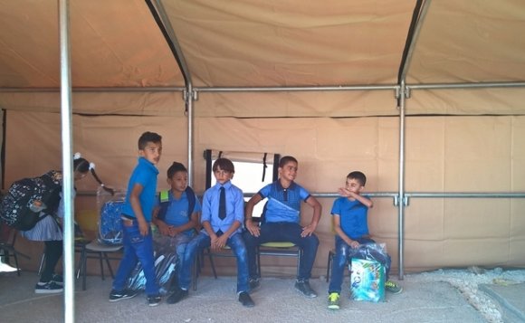 Des enfants palestiniens sont assis dans une tente installée pour remplacer les salles de classe en préfabriqué de Jubbet al-Dhib (MEE/Chloé Benoist)