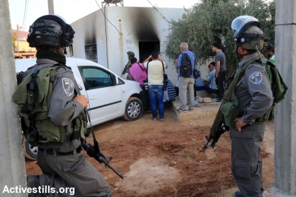Des membres de la Police des Frontières Israélienne devant l maison endommagée de la famille Dawabsha, qui a incendiée selon ce que l'on rapporte, par les colons israéliens, en tuant le Palestinien Ali Saad Dawabsha âge de 18 mois, dans le village de Duma en Cisjordanie, le 31 juillet 2015
