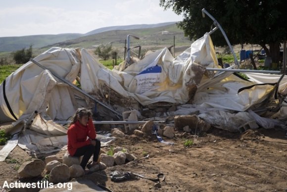 Une enfant est assise près de sa tente démolie, fournie par l'UE, dans le village de Fasayil dans la Vallée du Jourdain, en Cisjordanie le 10 février 2016. Ce jour-là les autorités israéliennes ont mené des démolitions importantes dans quatre zones de la Vallée du Jourdain. Sept maisons familiales et six abris pour les animaux ont été démolis, laissant 71 personnes sans toit au-dessus de leur tête. De plus, un ensemble de tuyaux qui apporte de l'eau à 300 personnes a été délibérément endommagé. (Activestills.org)