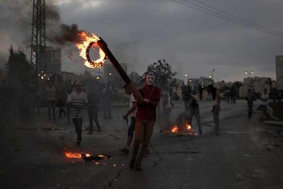 Un jeune Palestinien incendie des pneus au cours des affrontements avec les soldats israéliens à proximité de la colonie juive de Beit El, dans la ville cisjordanienne de Ramallah, suite à l'interdiction donnée aux Palestiniens le 4 octobre 2015 d'entrer dans la vieille ville de Jérusalem (AFP)