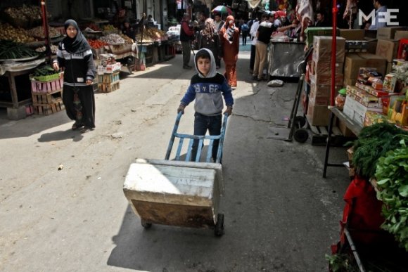 Un enfant palestinien transporte des denrées d'un étal à l'autre du marché (MEE/Mohammed Asad)