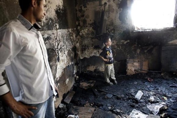 un Palestinien et un garçon se tiennent dans une maison incendiée par des colons israéliens dans le village cisjordanien de Duma. AFP