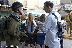 Un soldat et un colon pendant la visite de la vieille ville d'Hébron - 20/02/2010 - (c) Anne Paq/Activestills.org