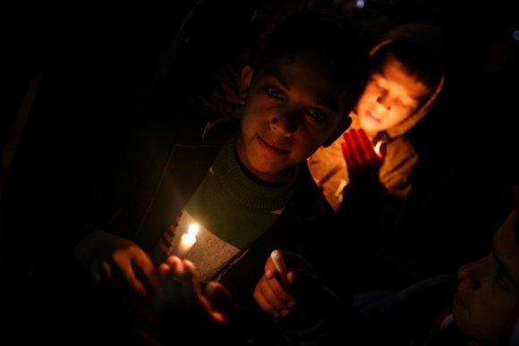 Des enfants de Gaza, bougies à main, participent à une manifestation organisée par les habitants qui réclament le droit à l'électricité (MEE/Mohamed al-Hajjar)